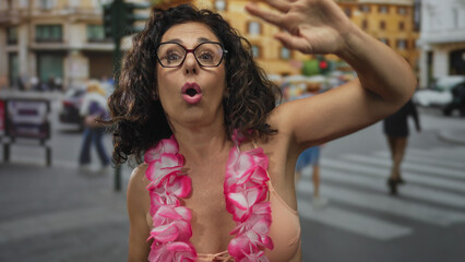 Woman in pink bikini and hawaiian lei raises hand and shouts on busy street; greeting energy celebration.