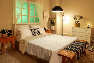 Interior of modern stylish bedroom with comfortable bed and glowing lamps