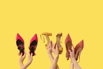 Female hands with different heels and sandals on yellow background