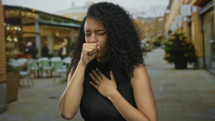 Fototapeta premium Woman coughing outdoors on a terrace with a blurred street background