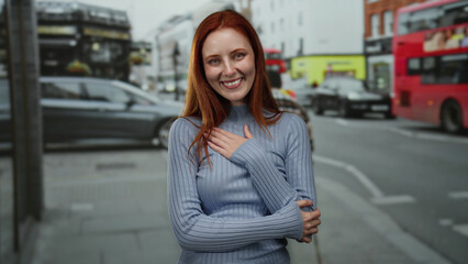 Woman smiling on city street with cars passing by, highlighted by vibrant red hair and casual outfit in urban outdoor setting suggesting british atmosphere.