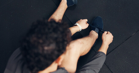 Above, athlete and tying laces with man at gym of fitness, start exercise and sports training. Male...