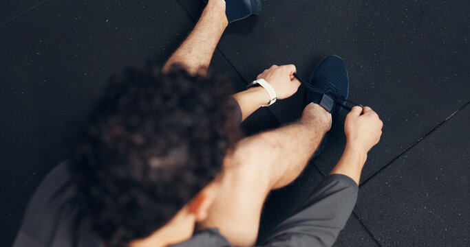 Above, athlete and tying laces with man at gym of fitness, start exercise and sports training. Male person, sneakers and getting ready for workout, practice preparation and footwear routine of health - Powered by Adobe