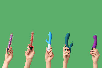 Female hands with different vibrators on green background