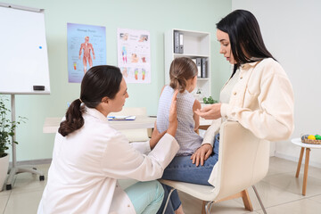 Obraz premium Mother and female osteopath working with little patient in clinic, back view