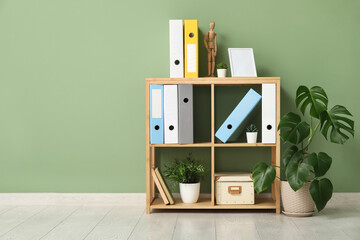 Shelf unit with document folders and plants near green wall in office