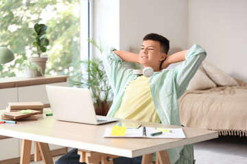 Teenage boy studying at table in bedroom