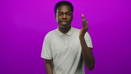 Man covering eye with hand in purple studio wearing glasses under soft bright light; mystery...
