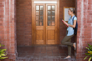 Double doors are standing framed by brick columns on tiled porch with bulletin board, potted plants
