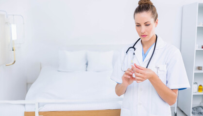 Woman doctor preparing syringe beside hospital bed in examination room with IV stand, copy space