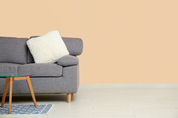 Comfortable sofa and coffee table near beige wall in room