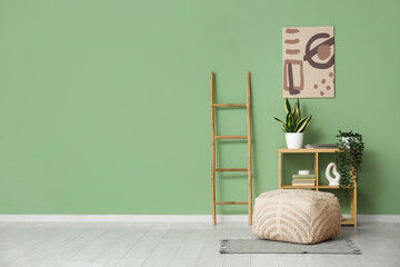 Shelving unit, ladder and pouf near green wall in room