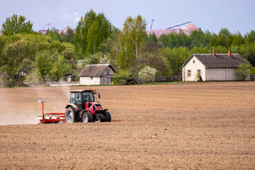 Farmer in tractor preparing farmland with seedbed for the next year. Powerful tractor at work,...
