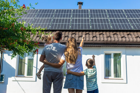happy family on the background of a house with solar panels on the roof. Selective focus