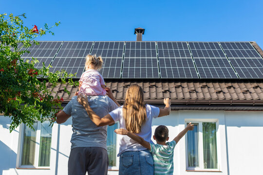 happy family on the background of a house with solar panels on the roof. Selective focus