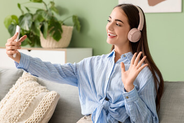 Young woman in headphones with diastema taking selfie at home