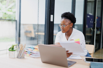 Young african american businesswoman wearing glasses and casual clothes is working with documents...