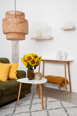 Stylish living room with green sofa and vase of beautiful sunflowers bouquet on coffee table,...