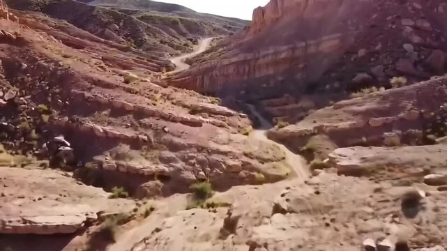 Red Rock Valley Trail: A stunning aerial view of a winding dirt track snakes through the rugged terrain, illustrating the majestic beauty of nature's raw, untouched earth.