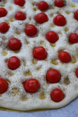 Not baked italian traditional Focaccia with red cherry tomatoes and thyme herb background