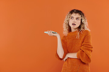 Vibrant young woman expresses curiosity with playful gesture against an orange background