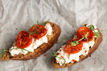Baking paper of tasty tomato bruschetta with ricotta, closeup