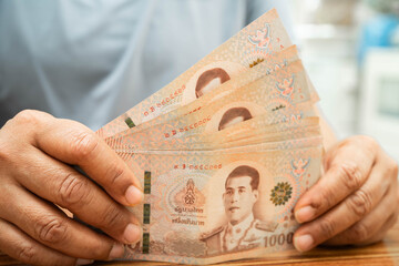 Asian woman counting Thai baht banknote money, investment economy, accounting business and banking.
