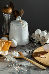 Ingredients for baking are arranged on a rustic table with eggs, flour, and kitchen utensils ready...