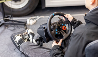 Back view of young man is enjoying car racing video game while sitting in chair and holding...
