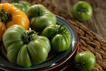 Fresh green tomatoes arranged on a colorful plate with a rustic background in a cozy kitchen setting