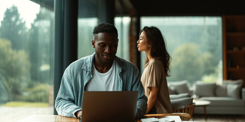 Mixed couple shares a joyful moment while working on a laptop in a Scandinavian home