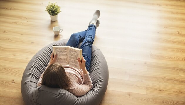 Young woman reading a book while relaxing on a beanbag chair
