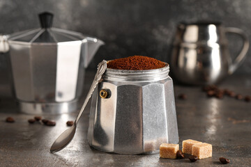 Geyser coffee maker with coffee powder on grey grunge background, closeup