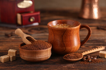 Bowl and spoon with coffee powder on wooden background, closeup