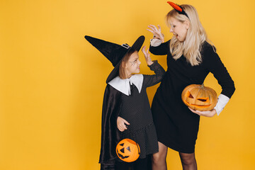 Mother and daughter wearing Halloween costumes playing with carved pumpkins