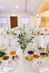 Tables are meticulously arranged for a festive gathering, showcasing colorful dishes, sparkling glassware, and a fresh floral centerpiece under soft lighting, creating an inviting atmosphere.