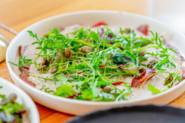 Salad of fresh herbs, arugula, lettuce, salt and sesame seeds in a white plate. Vegetarian, dietary dish