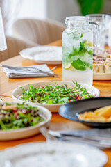 A sumptuous banquet with meat dishes accompanied by French fries, a variety of salads and drinks is served on the table. 