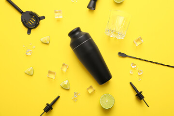 Composition with modern bartender kit, lime and ice cubes on yellow background