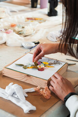 Woman arranging pressed flowers at a craft workshop