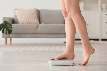 Legs of woman measuring weight on scales at home