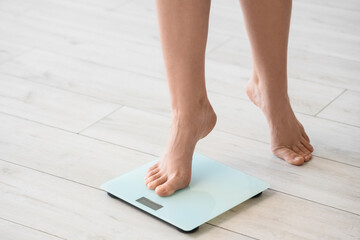 Feet of woman measuring weight on scales at home, closeup