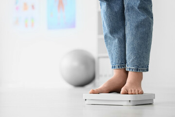 Legs of woman in jeans measuring weight on scales at home, closeup