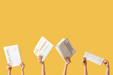 Female hands with newspapers on yellow background