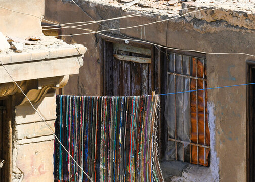 View of colorful fabrics hang drying from a weathered building against a backdrop of aged architecture, a slice of daily life, Zamalek, Cairo Governorate, Egypt.