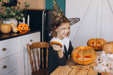 Young girl wearing witch hat carving pumpkins for Halloween party