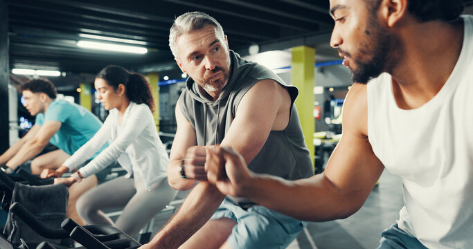 Fitness, men and fist bump on stationary bike at gym for cardio challenge, training and support. Athlete, people and celebration in spin class for cycling progress, teamwork and exercise performance