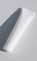 Blank white cosmetic tube with a cap, casting a soft shadow on a light background, perfect for skincare, beauty, or medical product branding mockups and packaging designs.
