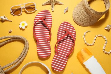Composition with stylish beach shoes, bottle of sunscreen cream and accessories on yellow...
