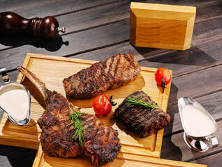 Delicious grilled meats served on wooden platter with garnish and sauce